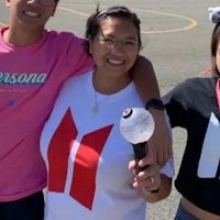 three young people posing for a photo in a parking lot